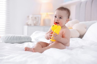 Photo of Cute baby with rubber duck after bathing on bed at home