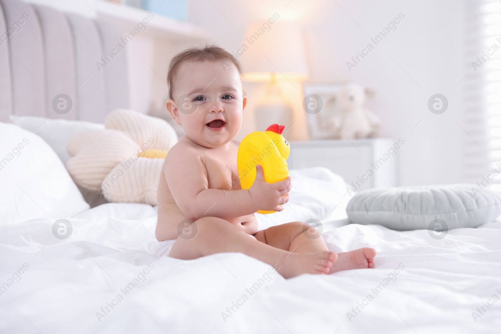 Photo of Cute baby with rubber duck after bathing on bed at home