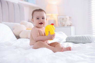 Photo of Cute baby with rubber duck after bathing on bed at home