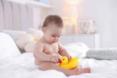 Photo of Cute baby with rubber duck after bathing on bed at home