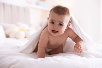 Photo of Cute baby wrapped with white towel after bathing on bed at home
