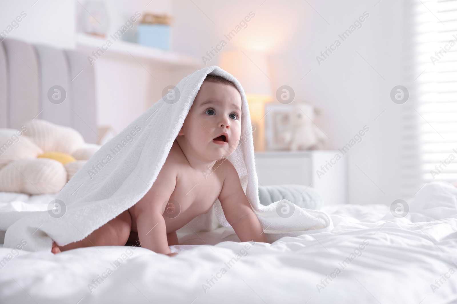 Photo of Cute baby wrapped with white towel after bathing on bed at home, space for text