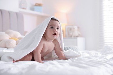 Photo of Cute baby wrapped with white towel after bathing on bed at home, space for text