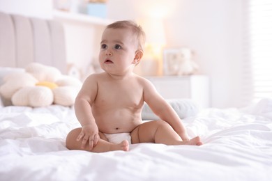 Photo of Cute baby in diaper after bathing on bed at home