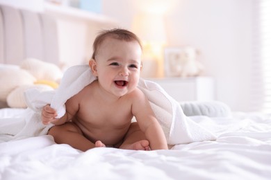 Photo of Cute baby wrapped with white towel after bathing on bed at home, space for text
