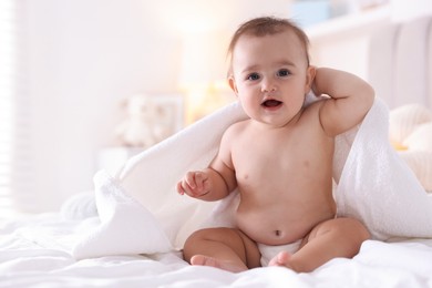 Photo of Cute baby wrapped with white towel after bathing on bed at home, space for text