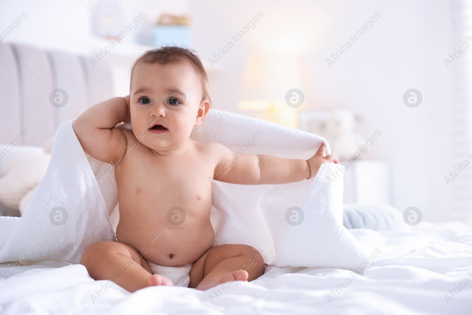 Photo of Cute baby wrapped with white towel after bathing on bed at home, space for text