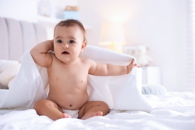 Photo of Cute baby wrapped with white towel after bathing on bed at home, space for text