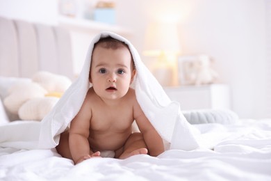 Photo of Cute baby wrapped with white towel after bathing on bed at home, space for text
