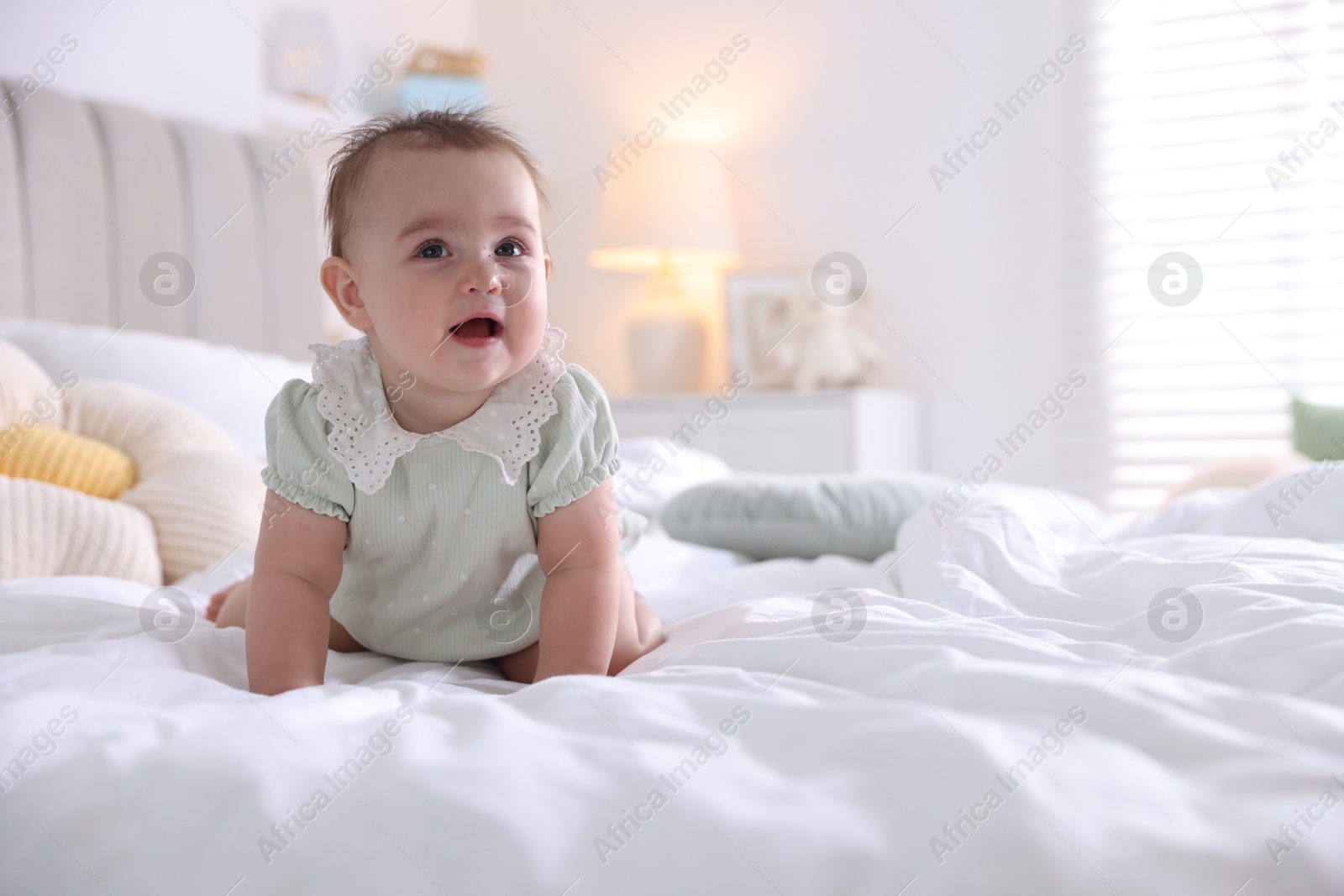 Photo of Cute little baby on bed at home, space for text