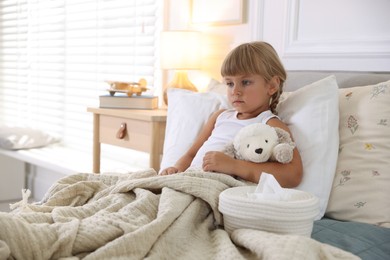 Photo of Sick little girl with her toy and tissues in bed at home. Space for text