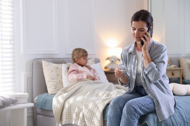 Photo of Telehealth. Mother and her sick daughter having consultation with doctor via phone on bed at home, selective focus