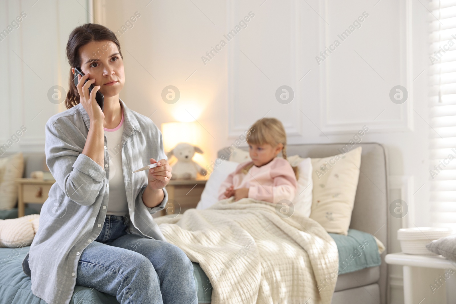 Photo of Telehealth. Mother and her sick daughter having consultation with doctor via phone on bed at home, selective focus
