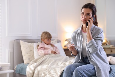 Photo of Telehealth. Mother and her sick daughter having consultation with doctor via phone on bed at home, selective focus