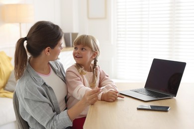 Photo of Telehealth. Mother and her daughter having online consultation with doctor via laptop at table indoors
