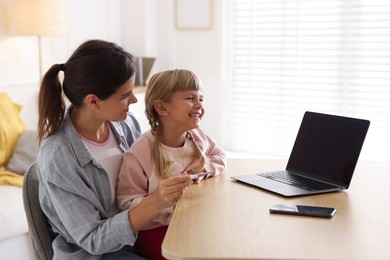 Photo of Telehealth. Mother and her daughter having online consultation with doctor via laptop at table indoors