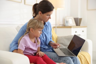 Photo of Telehealth. Mother and her sick daughter having online consultation with doctor via laptop on sofa at home