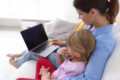 Photo of Telehealth. Mother and her sick daughter having online consultation with doctor via laptop on sofa at home