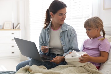 Photo of Telehealth. Mother and her sick daughter having online consultation with doctor via laptop on bed at home