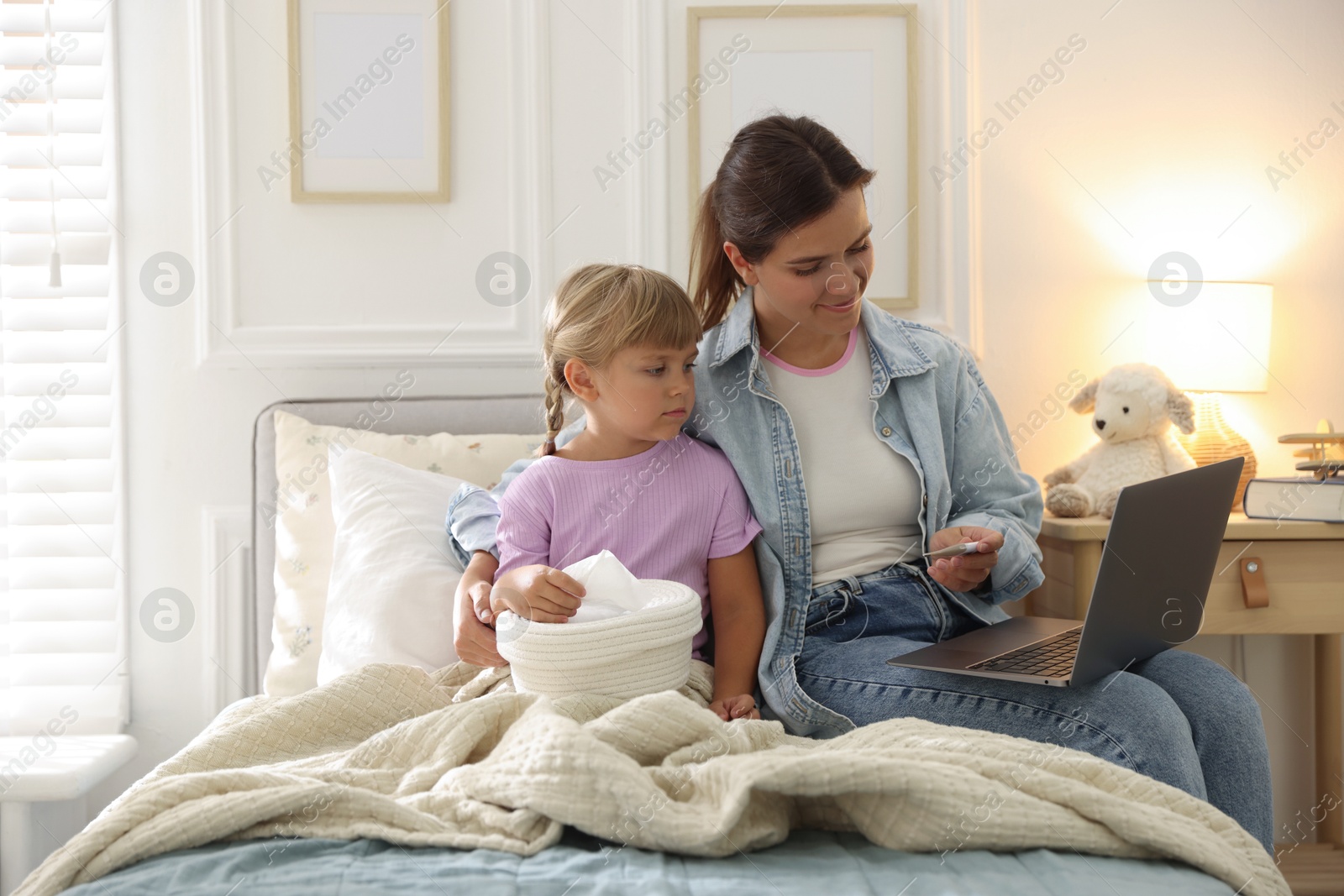 Photo of Telehealth. Mother and her sick daughter having online consultation with doctor via laptop on bed at home
