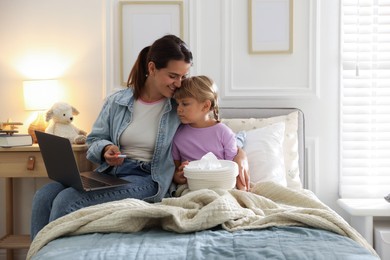 Photo of Telehealth. Mother and her sick daughter having online consultation with doctor via laptop on bed at home