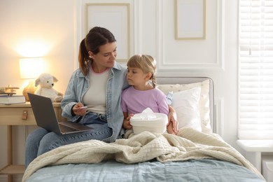 Photo of Telehealth. Mother and her sick daughter having online consultation with doctor via laptop on bed at home