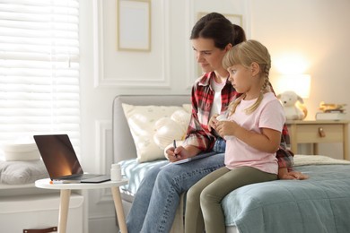 Photo of Telehealth. Mother and her daughter having online consultation with doctor via laptop on bed at home