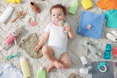 Photo of Cute baby, different clothes and accessories on floor, top view