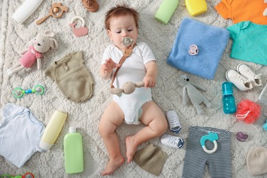 Photo of Cute baby, different clothes and accessories on floor, top view