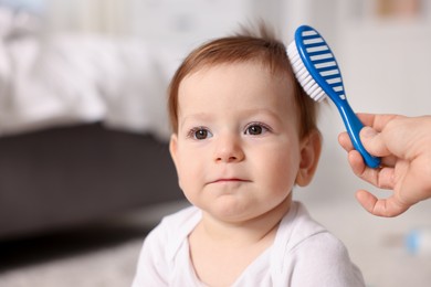 Photo of Mother brushing her baby's hair at home, closeup