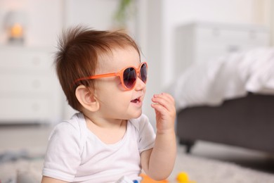 Photo of Cute baby with stylish sunglasses at home