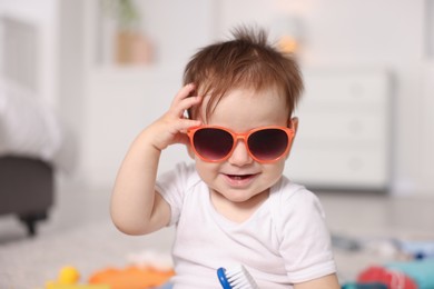 Photo of Cute baby with stylish sunglasses at home