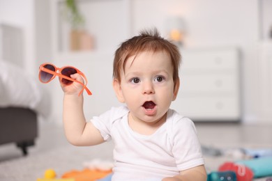 Photo of Cute baby with stylish sunglasses at home