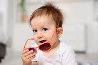 Photo of Cute baby with stylish sunglasses at home