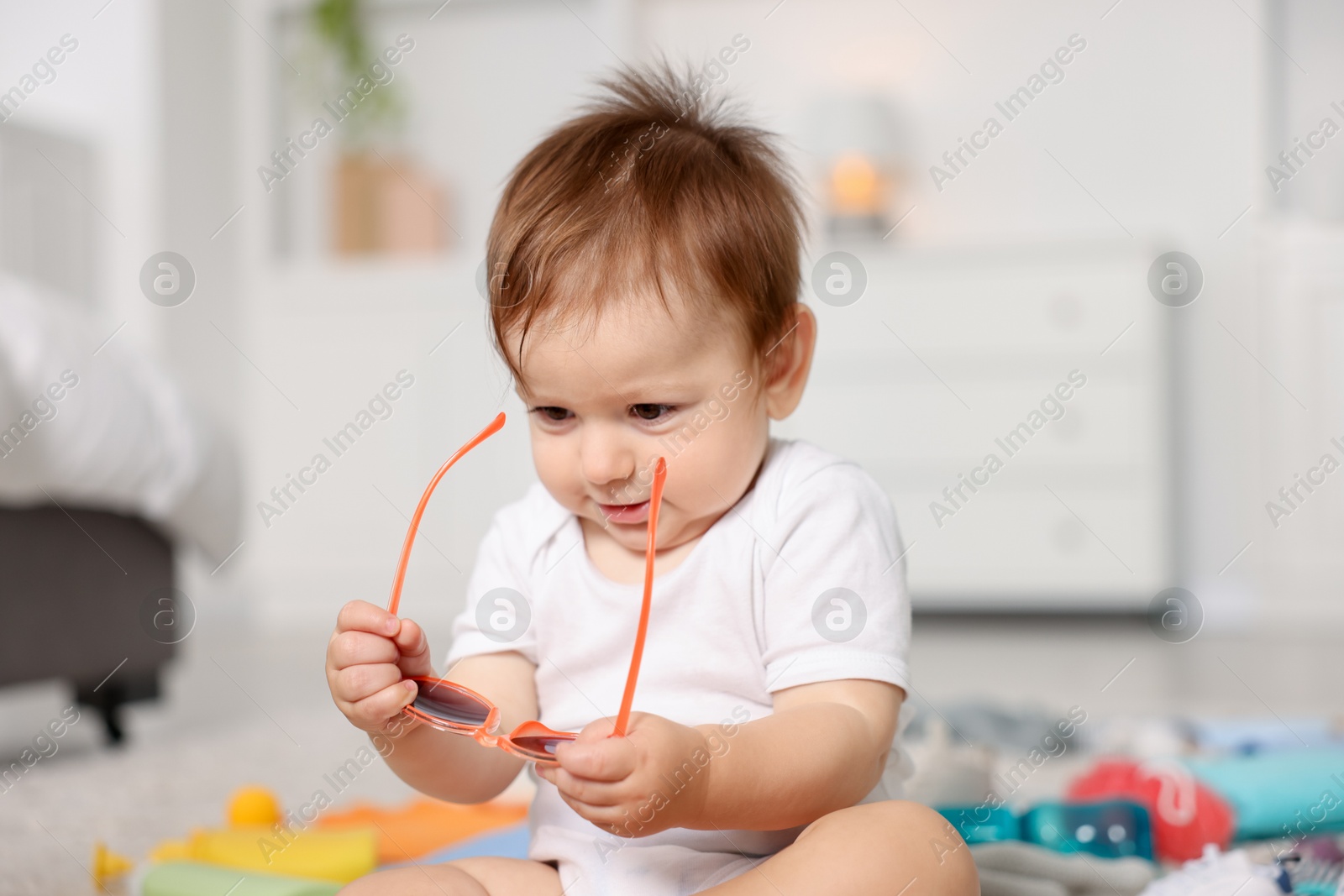 Photo of Cute baby with sunglasses on floor at home