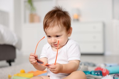 Photo of Cute baby with sunglasses on floor at home