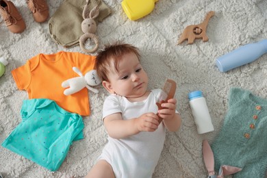 Photo of Cute baby, different clothes and accessories on floor, top view