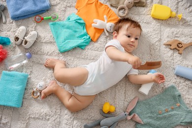 Photo of Cute baby, different clothes and accessories on floor, top view