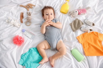 Photo of Cute baby, different clothes and accessories on bed, top view