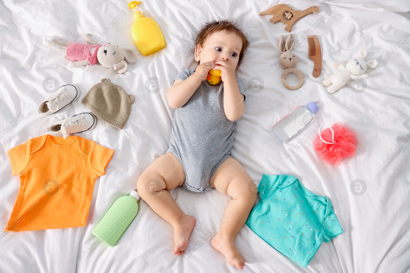 Photo of Cute baby, different clothes and accessories on bed, top view
