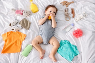 Photo of Cute baby, different clothes and accessories on bed, top view