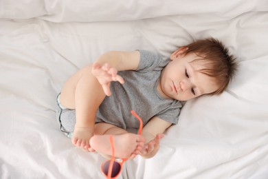 Photo of Funny baby with sunglasses lying on bed