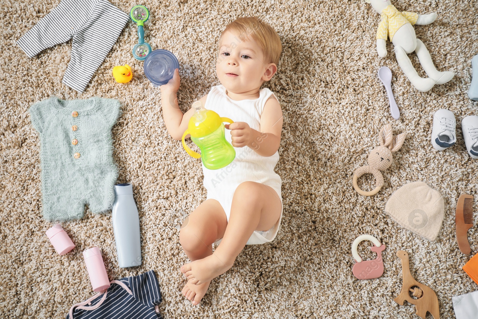 Photo of Cute baby, different clothes and accessories on floor, top view