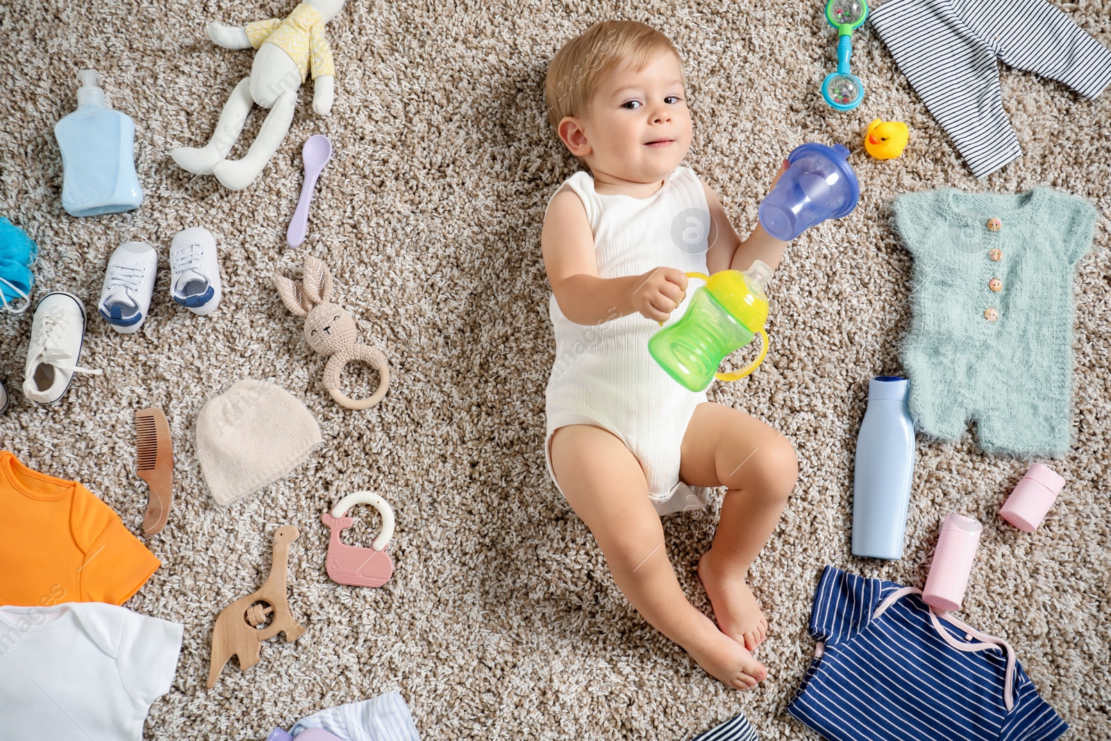 Photo of Cute baby, different clothes and accessories on floor, top view