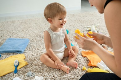 Photo of Mother playing with her cute baby at home, closeup