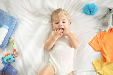 Photo of Cute baby, different clothes and accessories on bed, top view