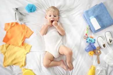 Photo of Cute baby, different clothes and accessories on bed, top view