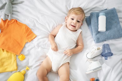 Photo of Cute baby, different clothes and accessories on bed, top view