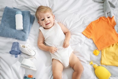 Photo of Cute baby, different clothes and accessories on bed, top view