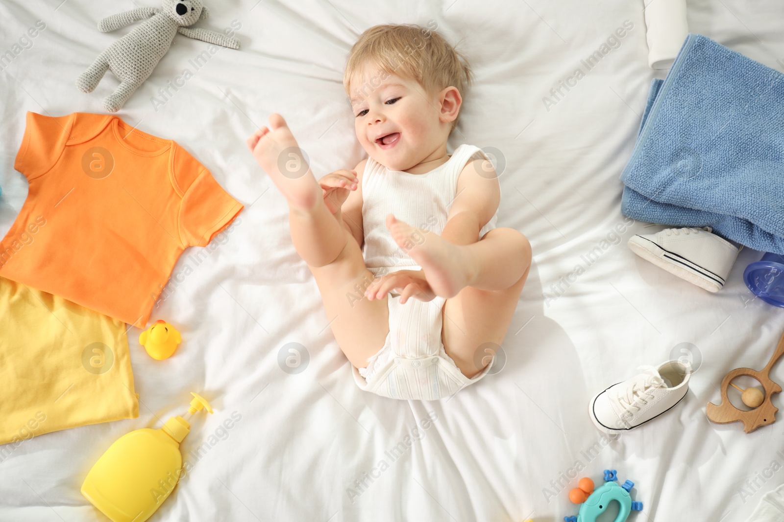 Photo of Cute baby, different clothes and accessories on bed, top view
